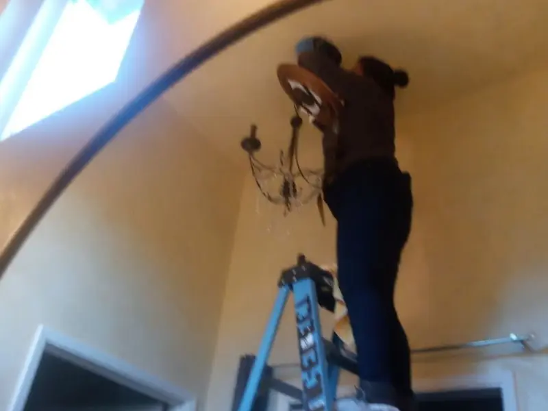 Electrician installing a chandelier in a Marietta residence